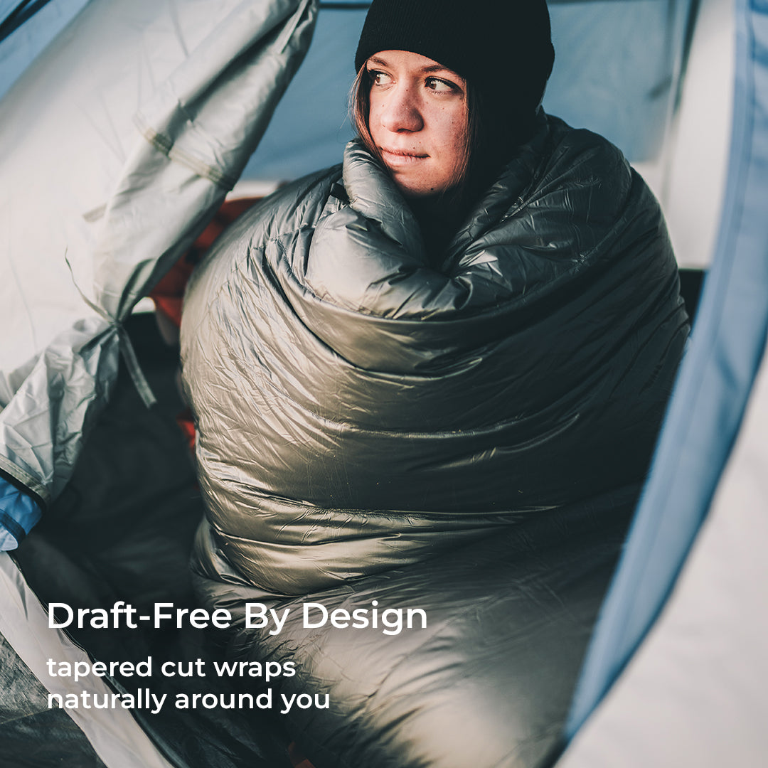 blue 0 degree quilt wrapped around woman inside tent
