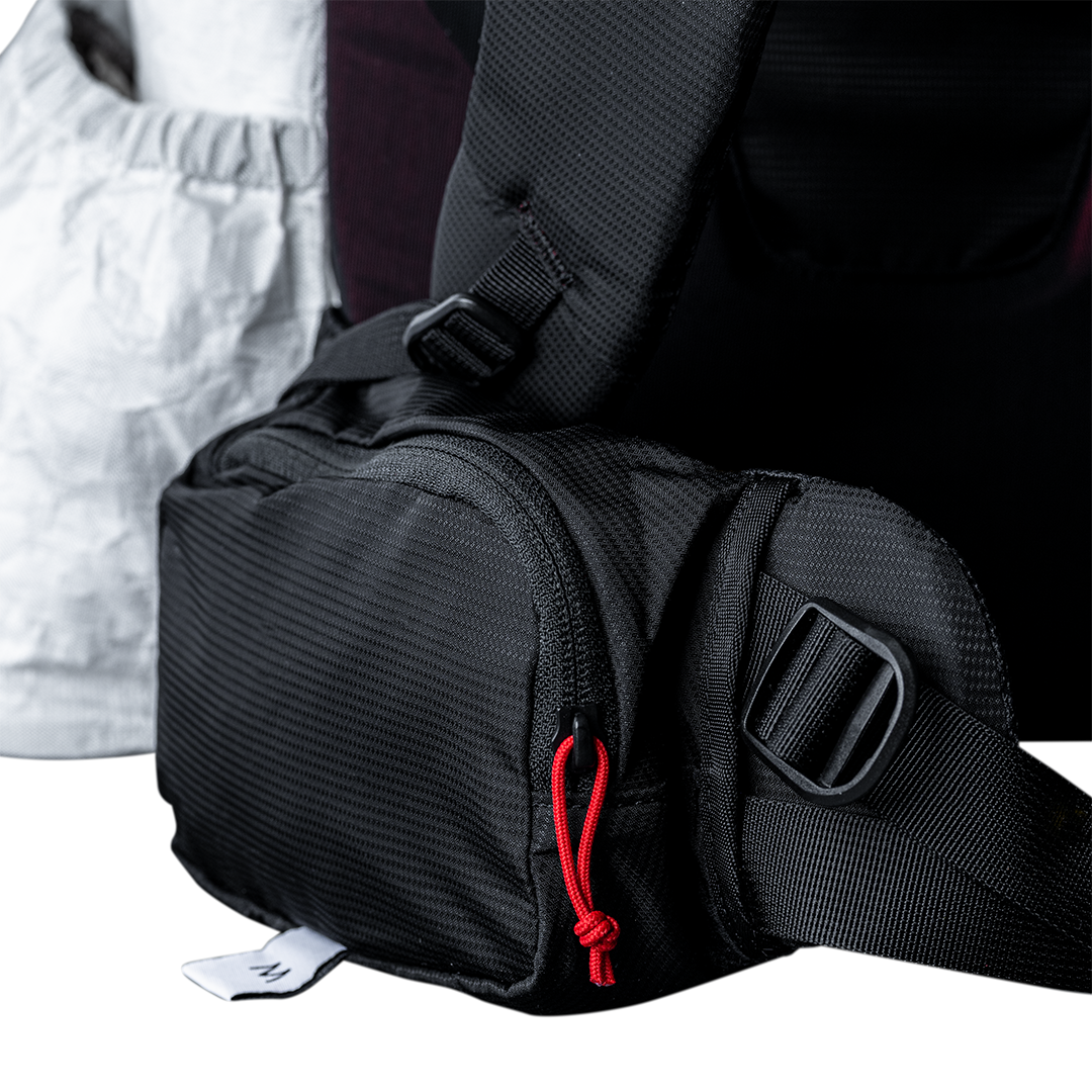 Close-up view of the Outdoor Vitals CS40 Ultra Backpack hip belt pocket, showing the zippered main compartment, cord zipper pull, and adjustable webbing strap.
