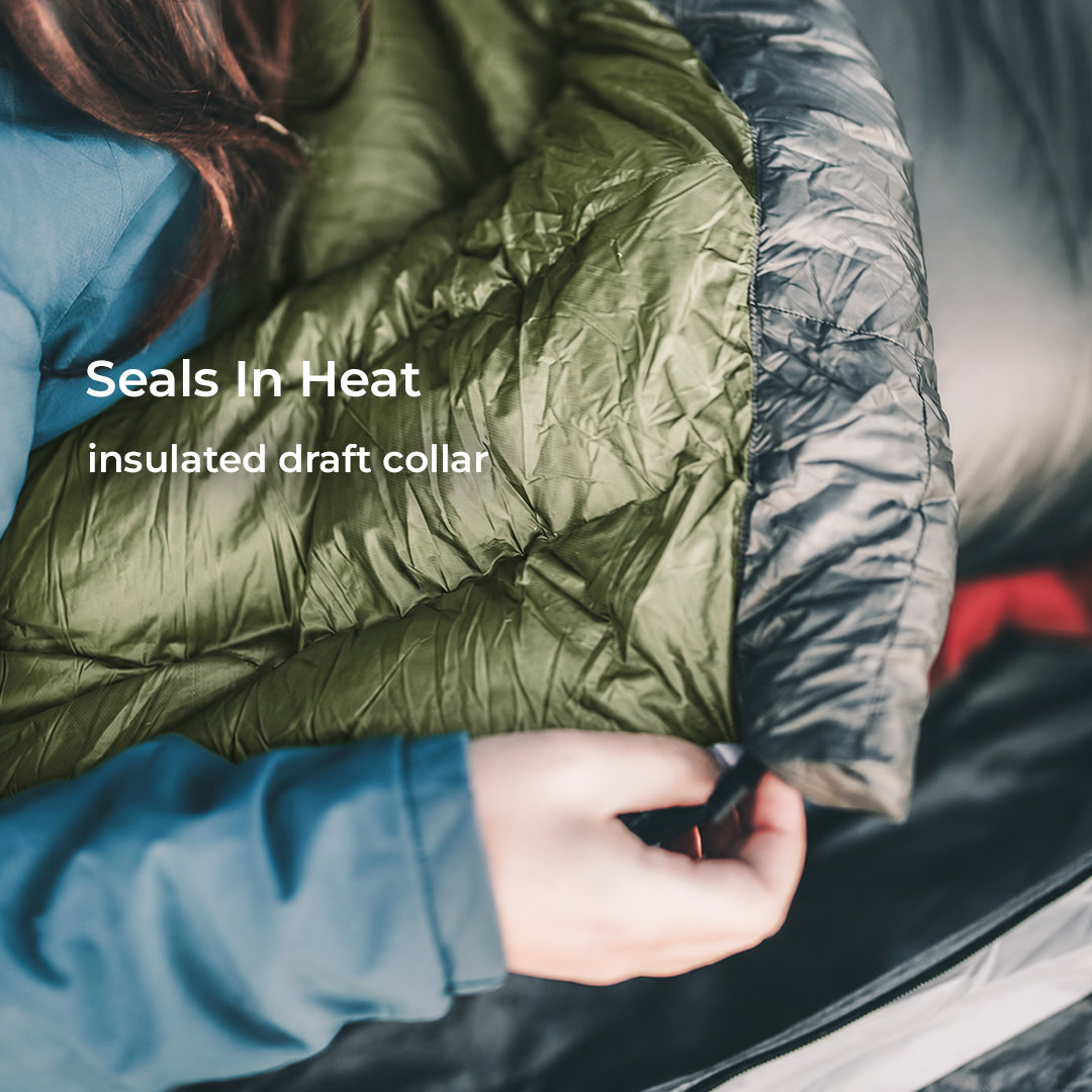 close view of box baffled draft collar on top quilt with green interior. Text says, "Seals In Heat, insulated draft collar."