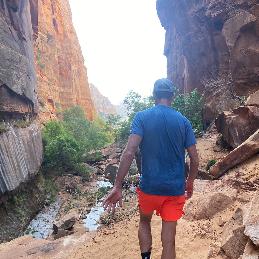 Hiker walking through a slot canyon wearing Outdoor Vitals Tern Ultralight Merino Wool Tee.