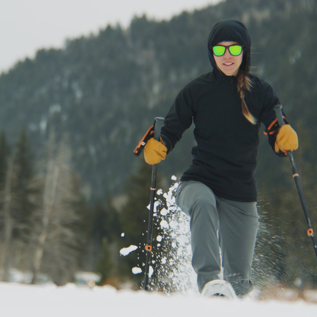 Woman snowshoeing with poles while wearing a Ventus Active Hoodie.
