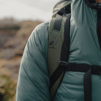 Close-up view of the padded shoulder strap on the Outdoor Vitals KotaUL Ultralight Travel & Adventure Backpack, showcasing the printed bird logo, ripstop fabric, breathable mesh padding, and adjustable sternum strap buckle.