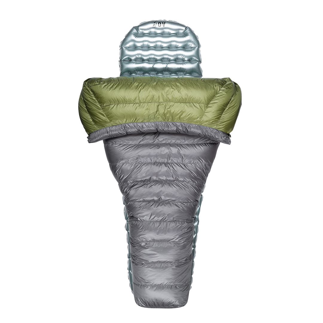 Top-down view of a backpacking quilt partially open, shown with a silvery inflatable sleeping pad inside.