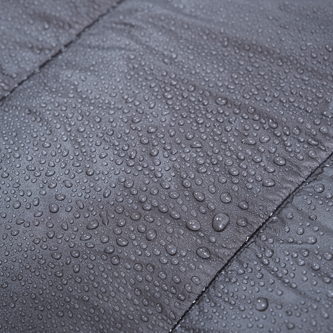 Close-up of water droplets beading on the surface of a quilt fabric, showing its water-resistant properties.