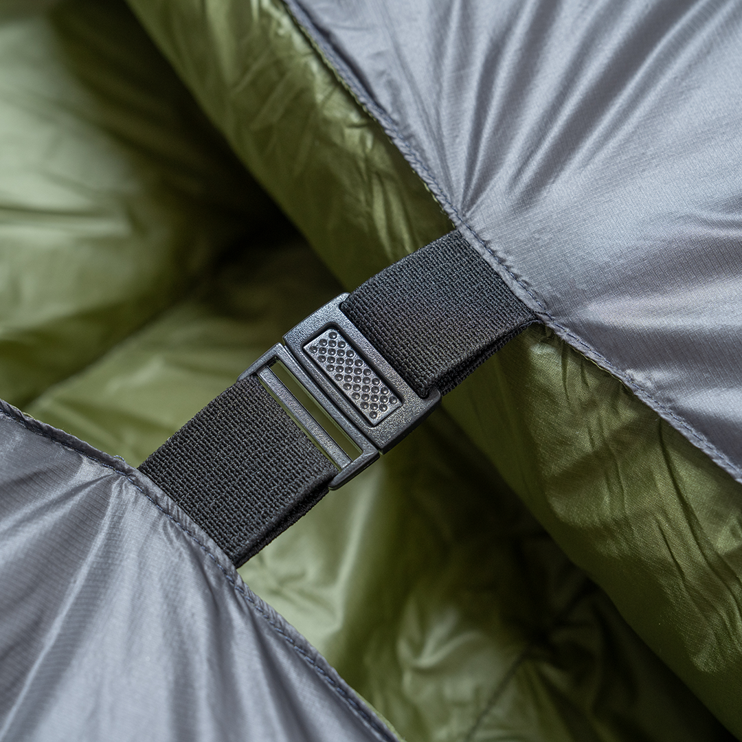 Close-up of a buckle and strap securing two sides of a backpacking quilt together.