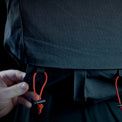 Close-up view showing a hand adjusting the bottom attachment point with elastic cord locks on the Outdoor Vitals Skyline 30 Fastpack, designed for securing gear like trekking poles or sleeping pads.