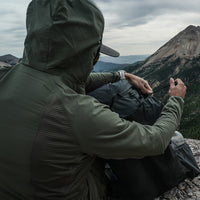 rear view of man wearing fleece hoodie on top of rugged mountain peak