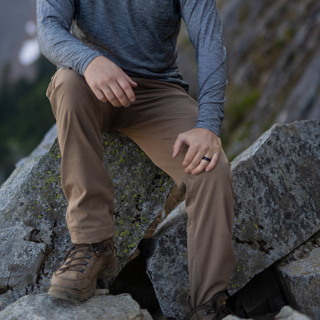 Hiker resting on rocks wearing Outdoor Vitals Satu Adventure Pants. all-groups
