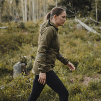 Woman in an hooded jacket and black leggings walking on an outdoor trail.