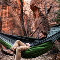 A camper relaxing in an Outdoor Vitals Ultralight Complete Hammock System equipped with an attached StormLoft Down UnderQuilt in a canyon landscape.