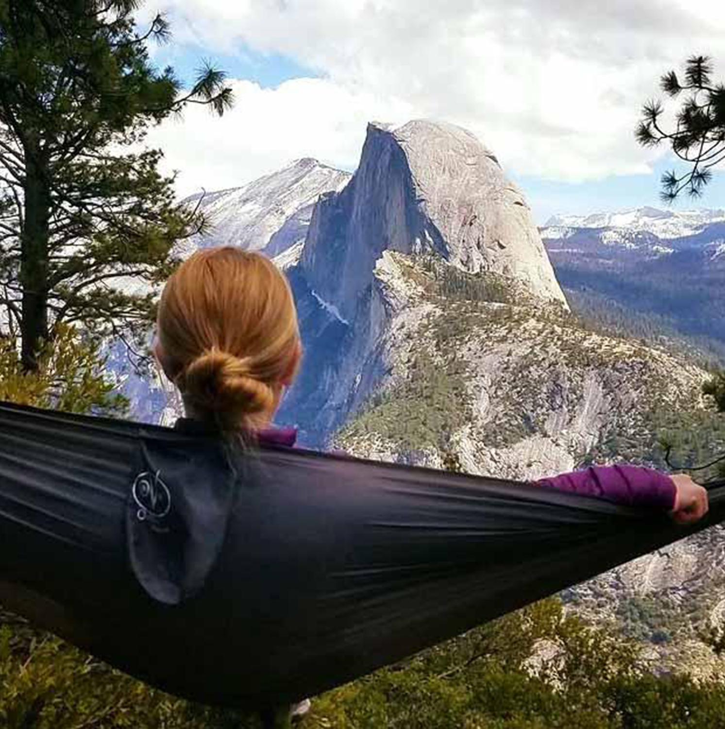 Rear view of a person lounging in an Outdoor Vitals Ultralight Hammock while overlooking Half Dome in Yosemite.