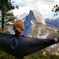 Rear view of a person lounging in an Outdoor Vitals Ultralight Hammock while overlooking Half Dome in Yosemite.