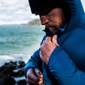 Close-up of a man adjusting a water-resistant Ventus Active Hoodie with water droplets on the sleeve by the sea.