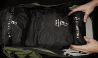Overhead view of hands placing packing cubes and accessory pouches into the fully unzipped main compartment of the Outdoor Vitals KotaUL Ultralight Travel & Adventure Backpack.