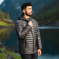 A man stands by a scenic mountain lake wearing a NovaUL jacket highlights the horizontal baffled quilting, a full-zip front, zippered hand pockets, and a fitted hood.